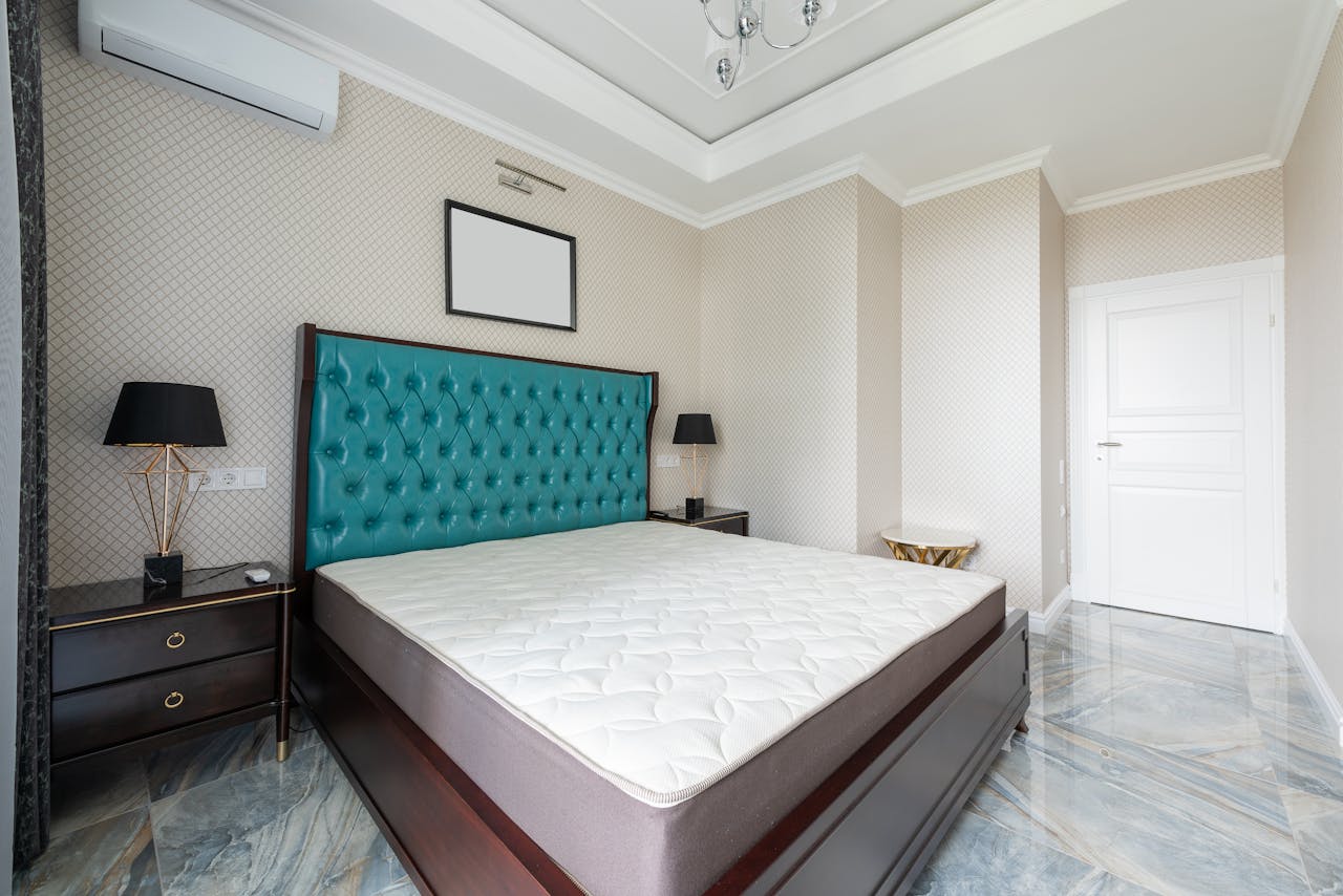 Stylishly designed modern bedroom with luxurious teal headboard and marble floor.